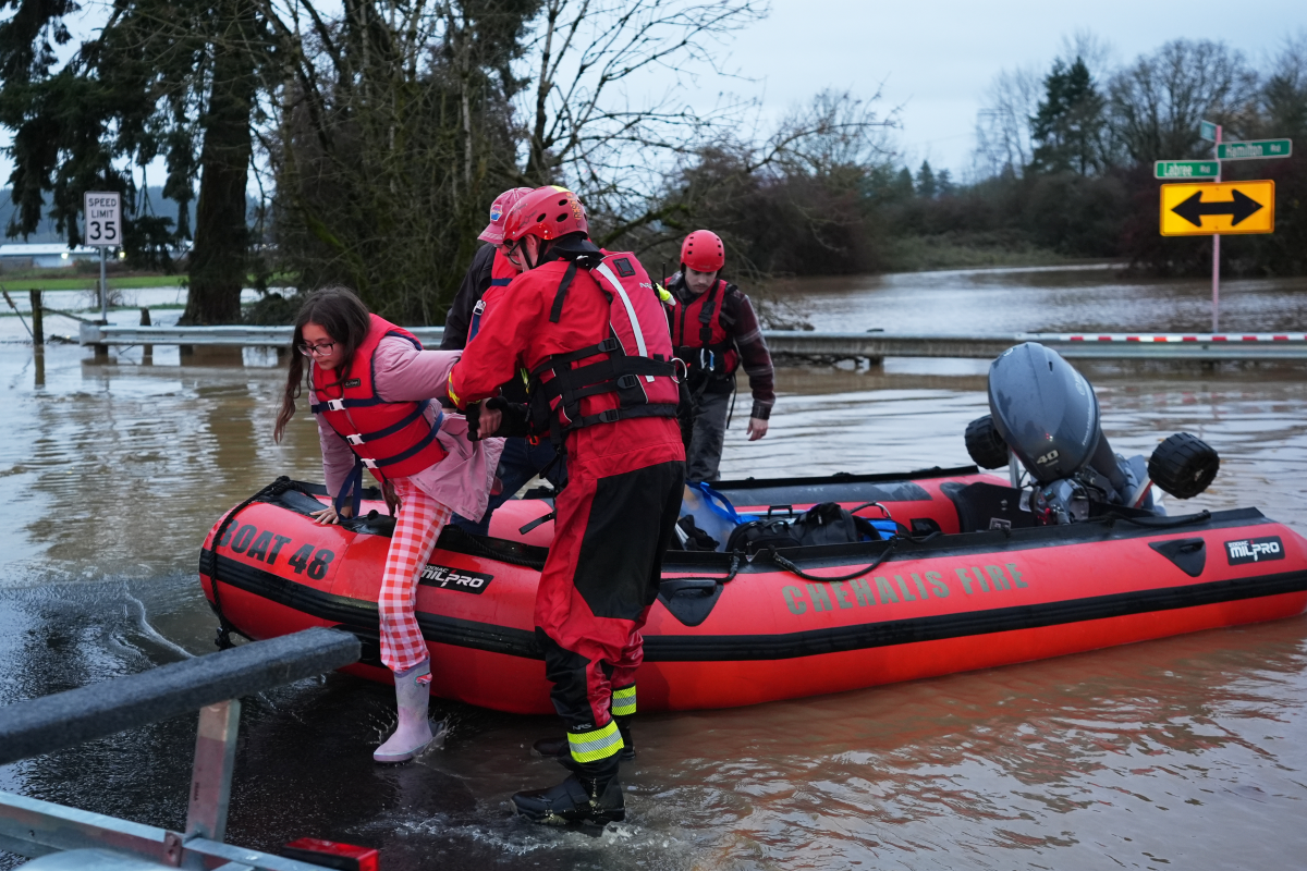 Maery Schine, 11, is helped out of a rescue boat by rescue workers with the Chehalis Fire Department after evacuating with her father, Patric (second from left), following flooding in Chehalis, Wash., on Tuesday.