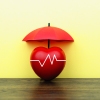 A photo illustration shows an apple with an EKG line across it, covered by an umbrella.