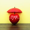 A photo illustration shows an apple with an EKG line across it, covered by an umbrella.