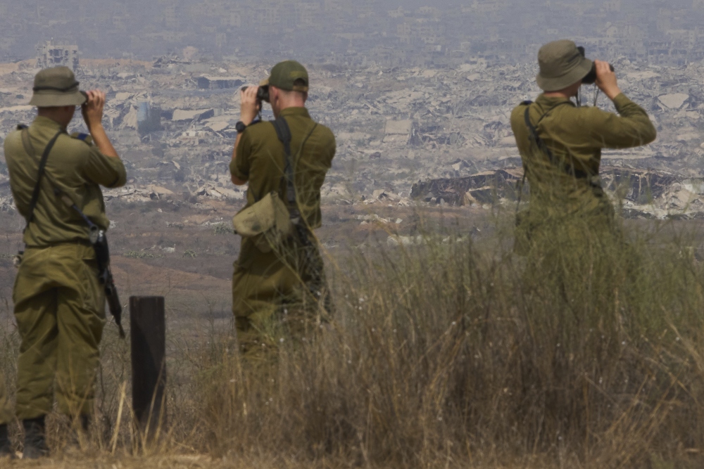 Israeli soldiers uses binoculars to look at damaged buildings in the Gaza Strip, from southern Israel, Wednesday, Aug. 13, 2025. (AP)
