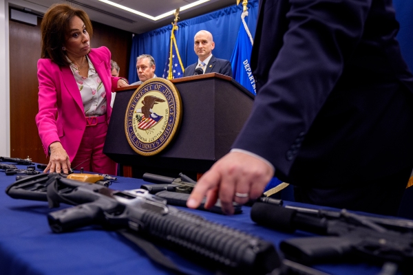 Jeanine Pirro, the U.S. attorney for the District of Columbia, looks at seized guns put on display on a table at an August 26, 2025, news conference.