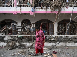 A woman salvages usable materials from her house deluged in sludge following flash floods at Devighat in Nepal's Nuwakot district.