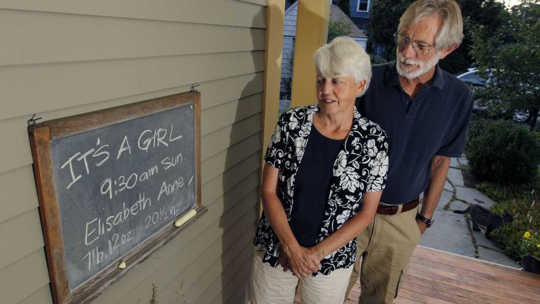 Eileen and Doug Flockhart look at a chalkboard announcing the birth of their seventh grandchild on the porch of their home in Exeter, N.H., Wednesday, Aug. 24, 2011.