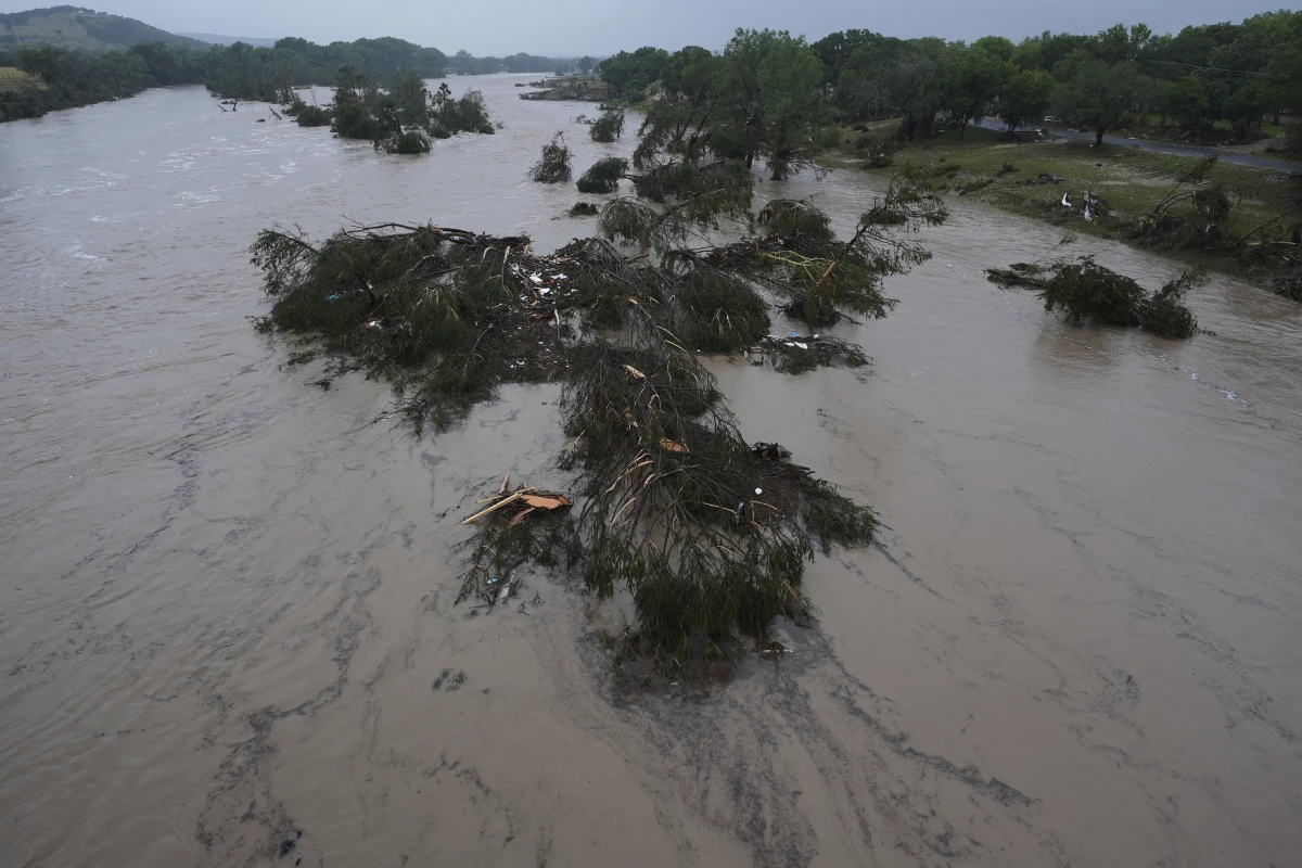 A raging Guadalupe River leaves fallen trees and debris in its wake in Kerrville, Texas.