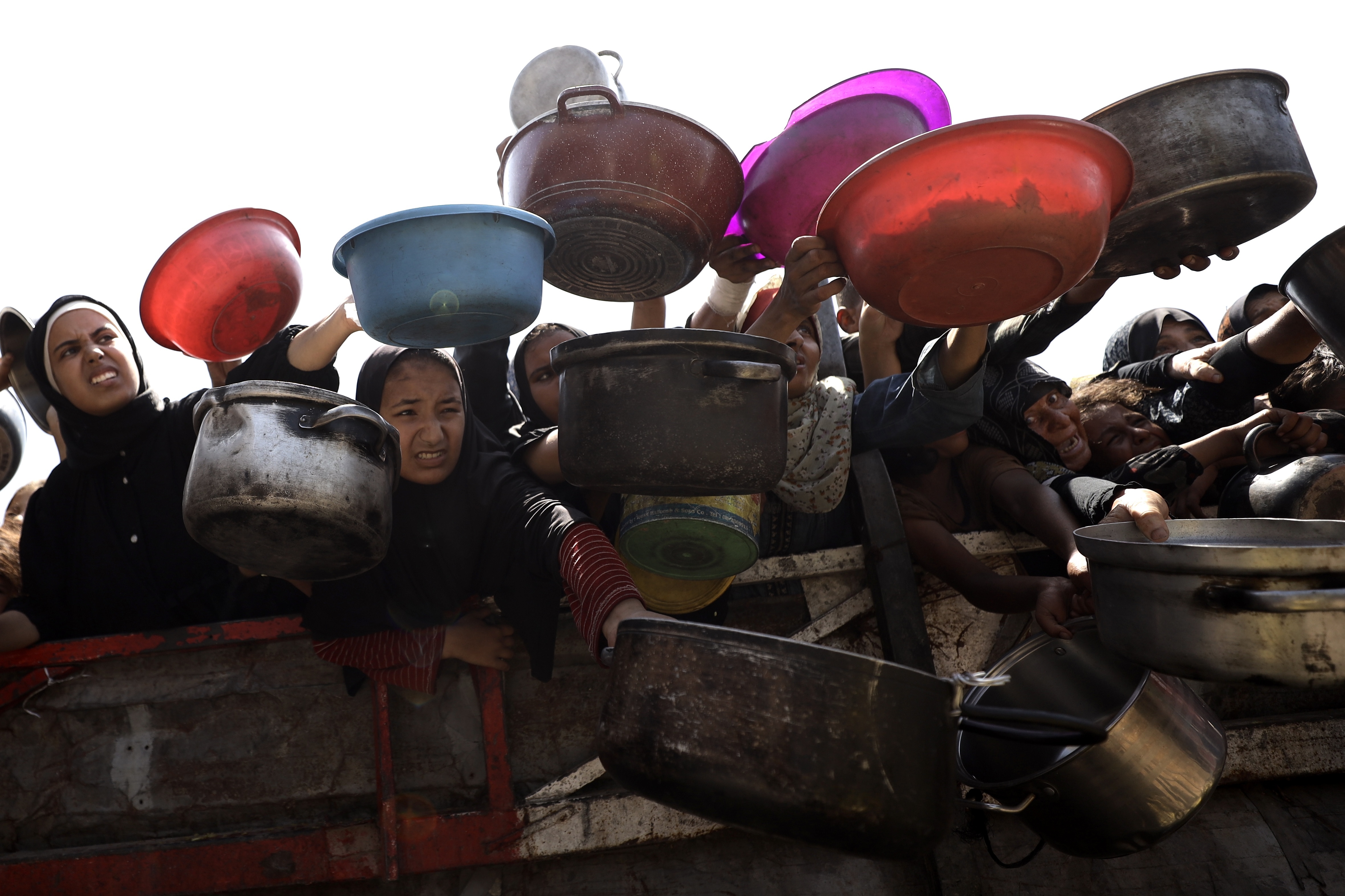 Palestinians, including children, receive hot meals, distributed by charity organizations, as people struggle to access food due to Israeli food blockade in Gaza City, Gaza on Aug.
