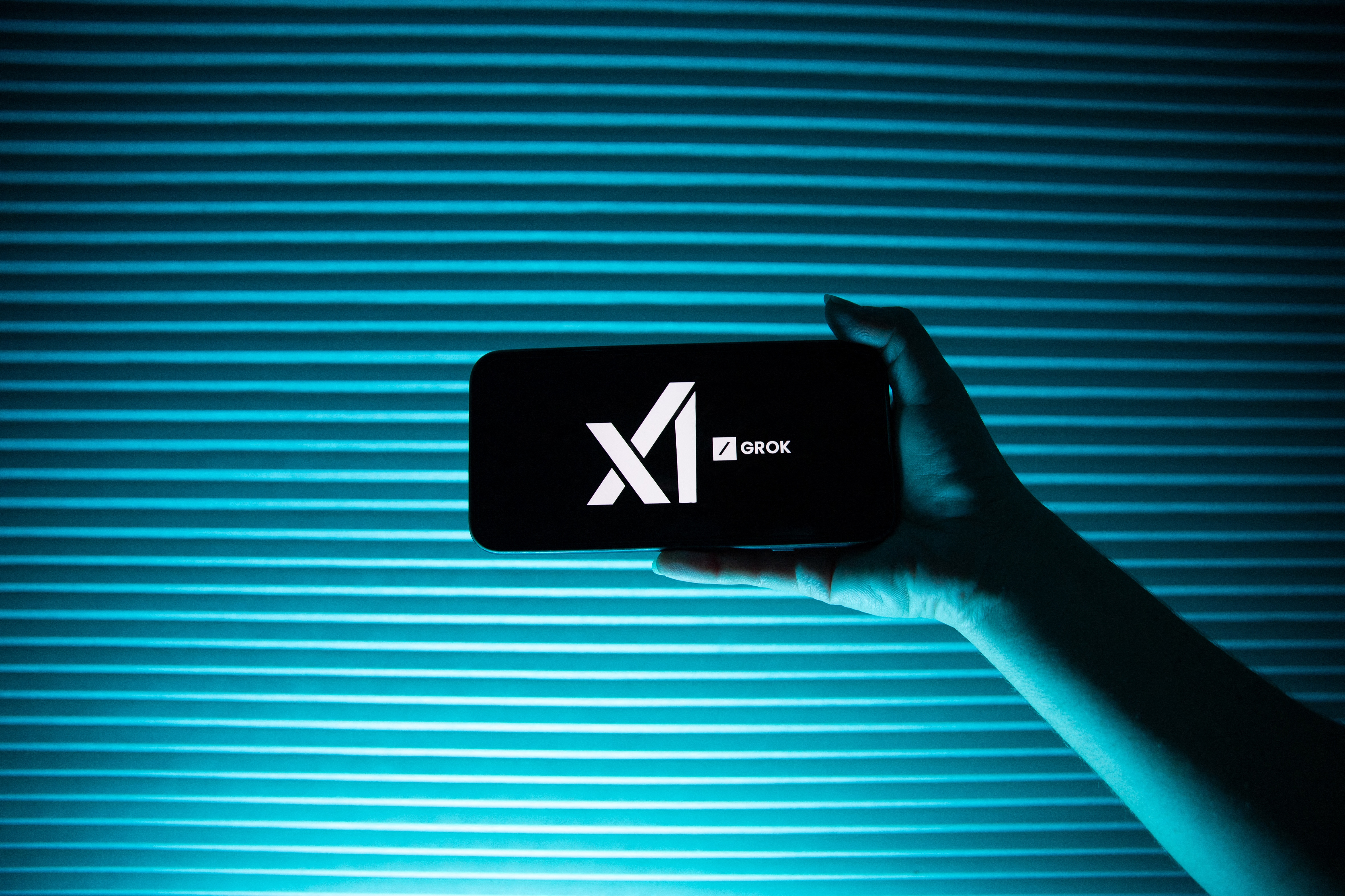 A person holds a telephone displaying the logo of Elon Musk