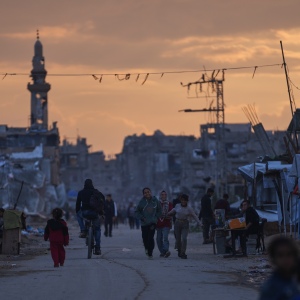 Palestinian youth walk along a tent camp for displaced people as the sun sets in Nuseirat, central Gaza Strip, Friday, Dec. 26, 2025.
