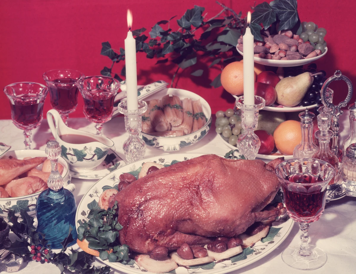 A traditional festive dinner table from 1955 decorated with sprigs of berried holly.