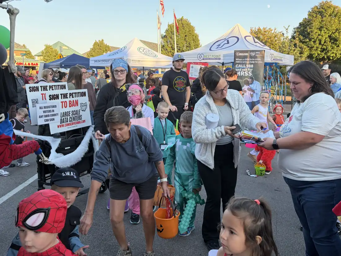 Linda Moodie (right), a volunteer with Conserve Ohio, collects signatures for a petition to ban large-scale data centers statewide at a Halloween event in Fairfield, Ohio, on Oct. 22, 2026.