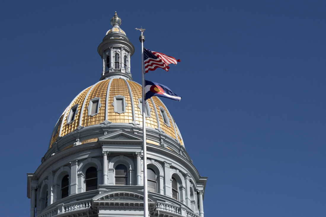 The U.S. and Colorado state flag fly in front of the dome at the Colorado State Capital in Denver in 2025.