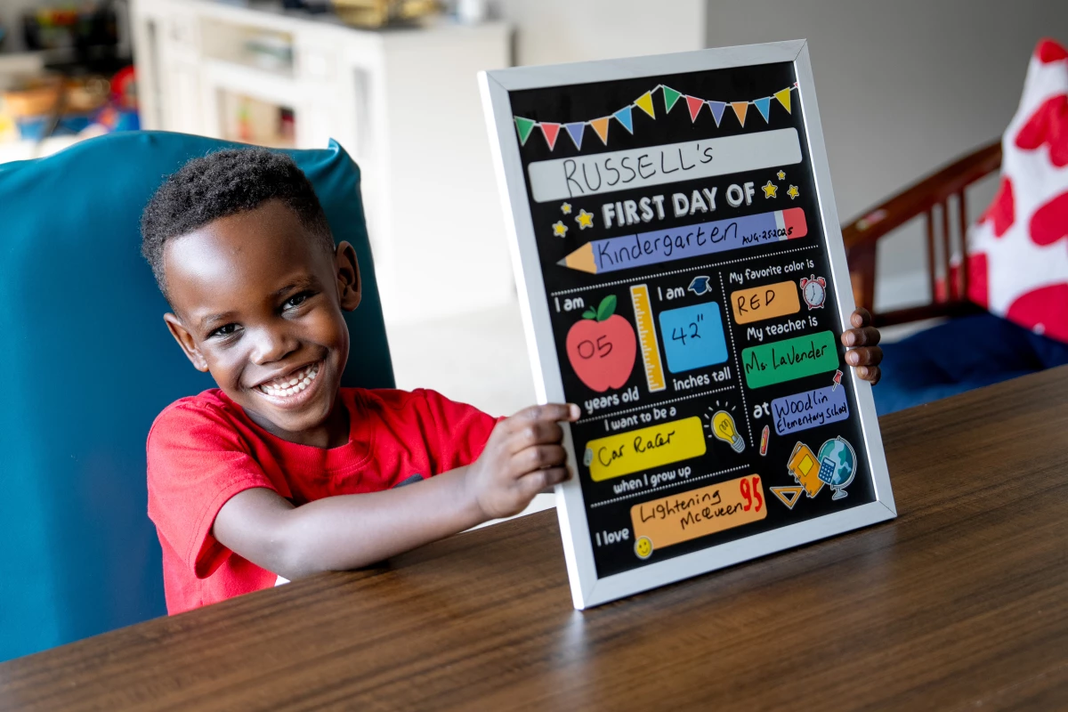 Russell shows off a placard commemorating his first day of kindergarten earlier this week.