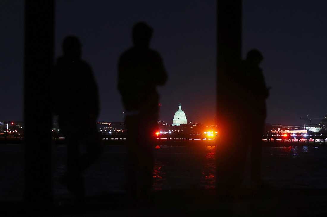 People watch as search and recovery efforts are underway on the Potomac