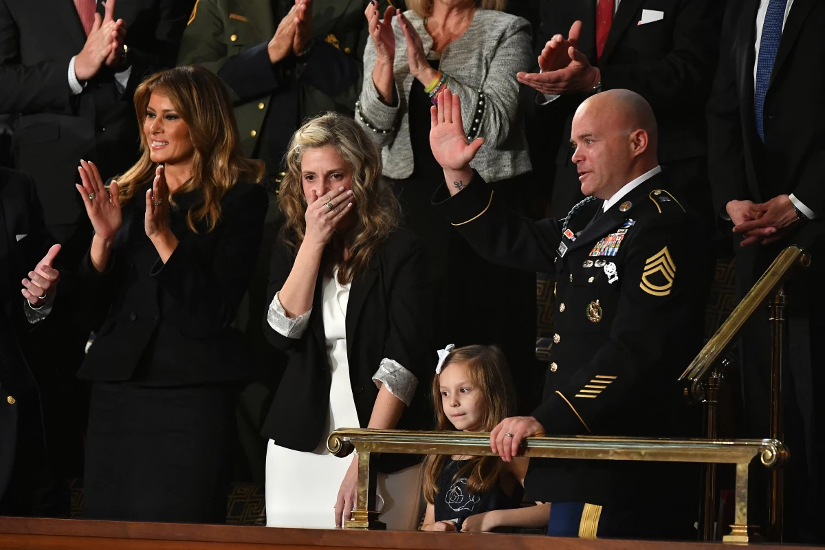Sgt. Townsend Williams (at right) waves after returning from deployment in Afghanistan, surprising his wife Amy during the 2020 State of the Union address.