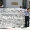 Mary Rodee, whose 15-year-old son died by suicide, points to a banner listing victims' names outside Los Angeles Superior Court.