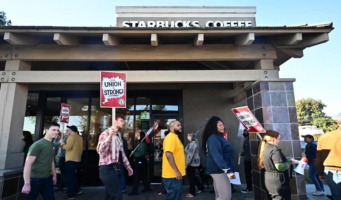 Starbucks workers hold signs as they picket in Burbank, California on Friday.