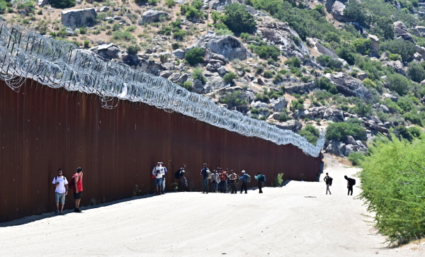 Migrants walk into the US beside the US-Mexico border wall at Jacumba Hot Springs, California, on June 5, 2024. Migrants from countries such as Turkey, Jordan, Guatemala, Nicaragua, China and India made their way on foot into the United States today before being met with by Customs and Border Patrol agents for processing. The United States will temporarily close its Mexico border to asylum seekers from June 5, as President Joe Biden tries to neutralize his political weakness on migration ahead of November's election battle with Donald Trump. (Photo by Frederic J. BROWN / AFP) (Photo by FREDERIC J. BROWN/AFP via Getty Images)