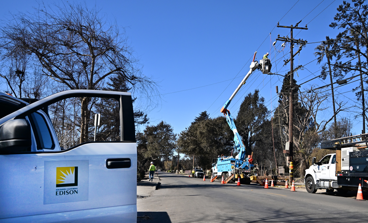 Workers work on repairing and restoring power lines on Jan. 13, in Altadena, where the devastating Eaton Fire caused widespread damage.