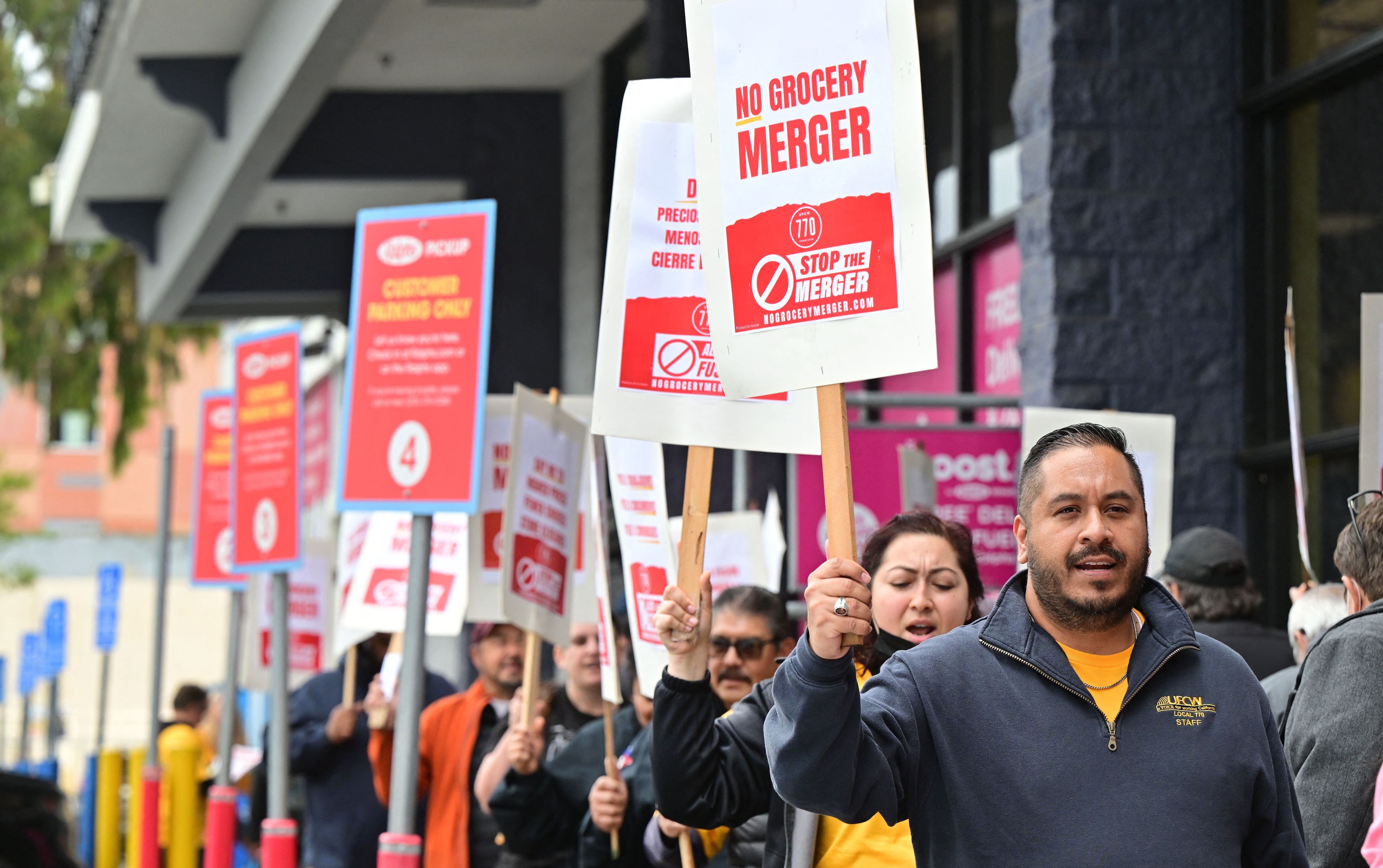 Unionized grocery store workers rally to oppose the proposed merger between Kroger and Albertsons outside a Ralph