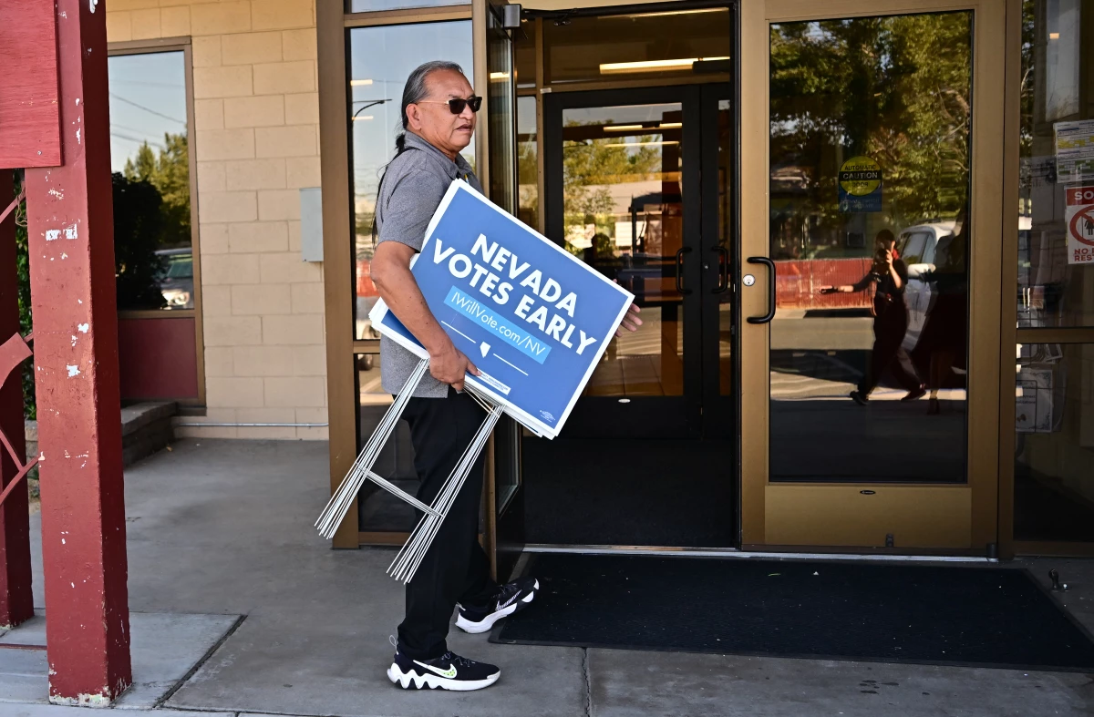 Little Buck Harjo carries 'Nevada Votes Early' signs at the reno-Sparks Indian Colony in Reno, Nev., on Oct. 15, 2024.