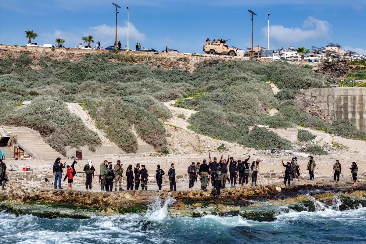 This aerial view shows members of security forces loyal to the interim Syrian government standing along a rocky beaech by Mediterranean sea coast in Syria's western city of Latakia on March 9.