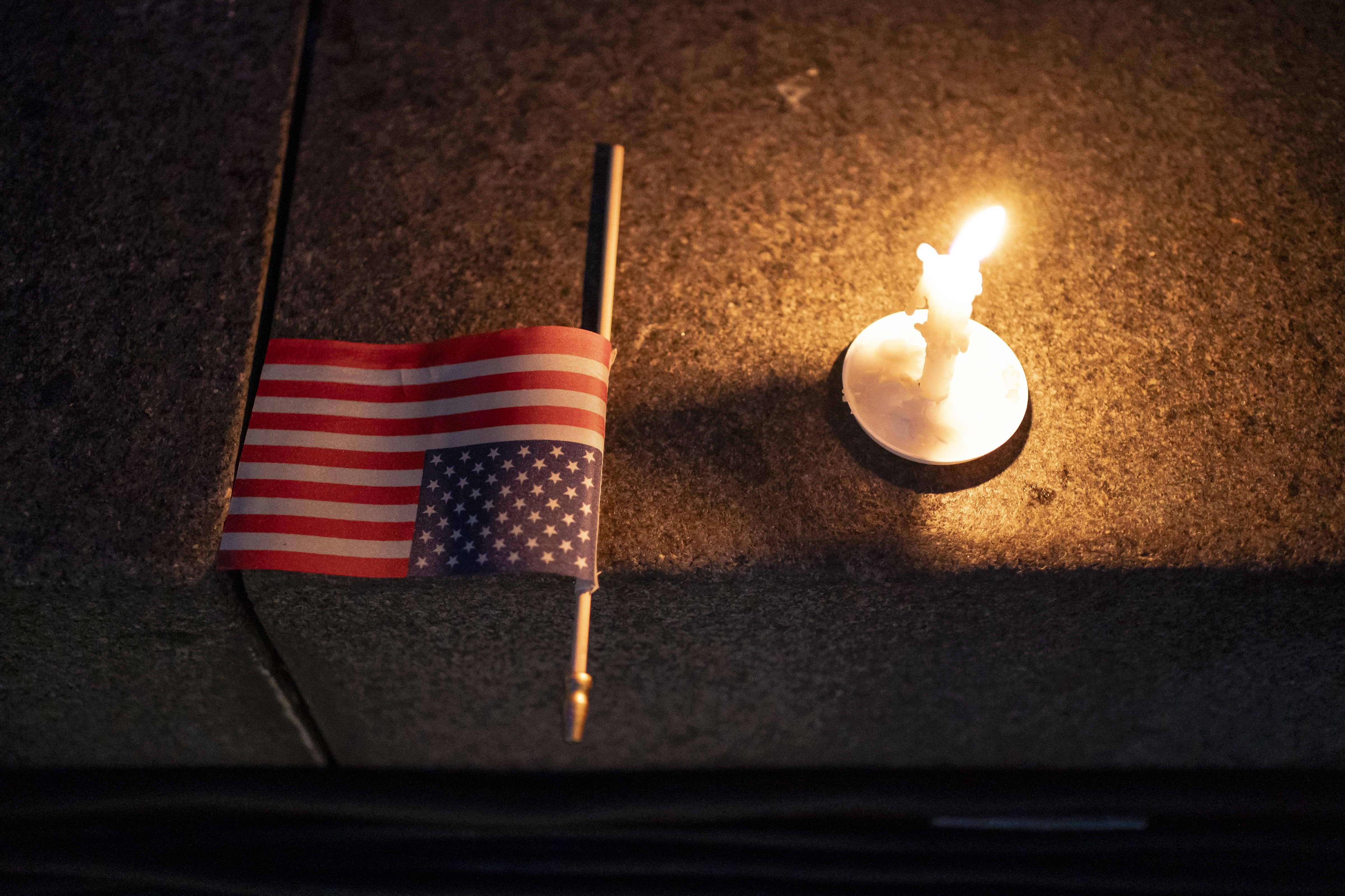 A U.S. flag and a candle sit on a step during a candlelight vigil and prayer event for Turning Point USA Founder Charlie Kirk on Sept. 10 in Seattle. Kirk was shot dead while speaking at Utah Valley University earlier in the day.