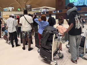 A group of Ugandan men and women line up to board their flight back home, after being released from scam compounds in Cambodia and then enduring compounding hardship on the streets of Phnom Penh.