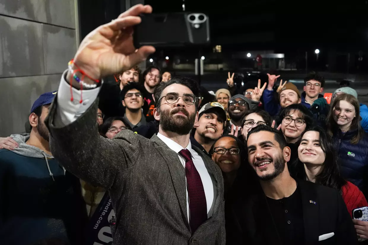 Streamer Hasan Piker, left, and Abdul El-Sayed, a progressive candidate in the Democratic primary for U.S. Senate in Michigan, center right, take a selfie with young fans following a campaign event on April 7, 2026, at the University of Michigan in Ann Arbor.
