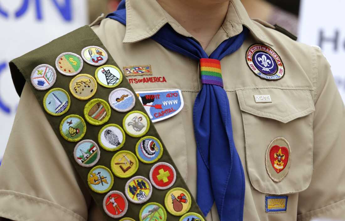 FILE - Merit badges and a rainbow-colored neckerchief slider are affixed on a Boy Scout uniform. The U.S. organization, which now welcomes girls into the program and allows them to work toward the coveted Eagle Scout rank, announced May 7, 2024, that it would change its name to Scouting America as it focuses on inclusion.