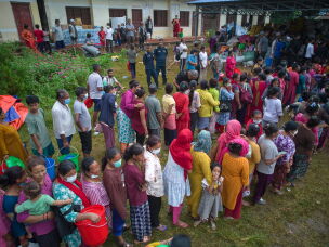 People affected by recent flash floods stand in line to receive aid at a school converted into a temporary shelter in Nepal's Nuwakot district, Thursday.