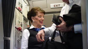 A female flight attendant greets a passenger leaving the plane.