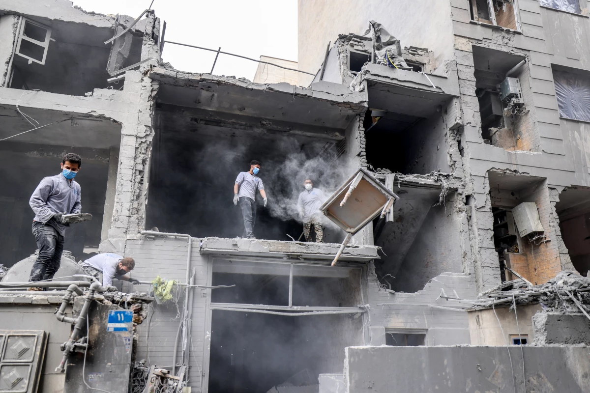 Iranians clear the debris from damaged homes following a military strike in Tehran on March 15.