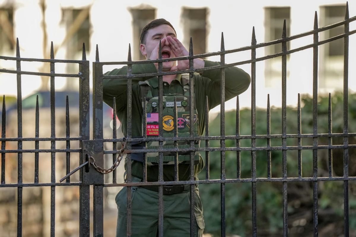 Jake Lang shouts from a sidewalk as New York Mayor Zohran Mamdani speaks during a news conference at Gracie Mansion, Monday, March 9, 2026, in New York.