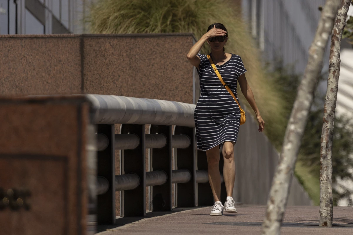 A woman shields her eyes from the sun as she walks in downtown Los Angeles during a heatwave Friday, Sept. 6, 2024.