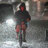 A man rides his bike along a flooded road near Chiba metro station in Chiba, Japan, on Aug. 13, 2026, as heavy rain swept through the area. Torrential rain pummeled eastern Japan, triggering landslides and power outages, and prompting the weather authority to issue its highest-level heavy rain warning for the region for the first time.