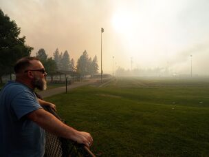 Andrew Rowley watches Old Trails Fire from Dwight Merkel Sports Complex after evacuating, on Aug. 1, 2026, in Spokane, Wash.