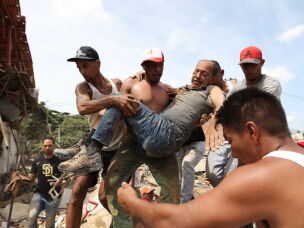 Neighbors carry a man rescued from the rubble of a collapsed building on Thursday, the day after earthquakes struck La Guaira, Venezuela.