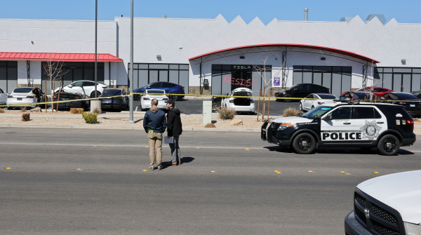 Investigators look over the scene at a Tesla Collision Center after a person set several vehicles on fire on Tuesday in Las Vegas.
