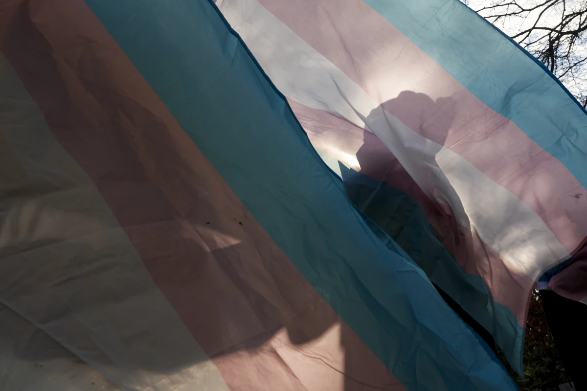 A protester is silhouetted against a trans pride flag during a pro-transgender rights protest outside of Seattle Children's Hospital, in Seattle, on Feb. 9.