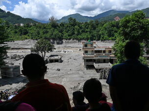 People watch from a rooftop as houses lay deluged in sludge after flash floods at Trishuli in Nepal's Nuwakot district.