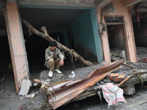 A man sits amidst debris of a house deluged in sludge following flash floods at Devighat in Nepal's Nuwakot district.