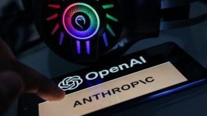 A smartphone displaying the OpenAI logo above the word "Anthropic" is seen beside a lit headset.