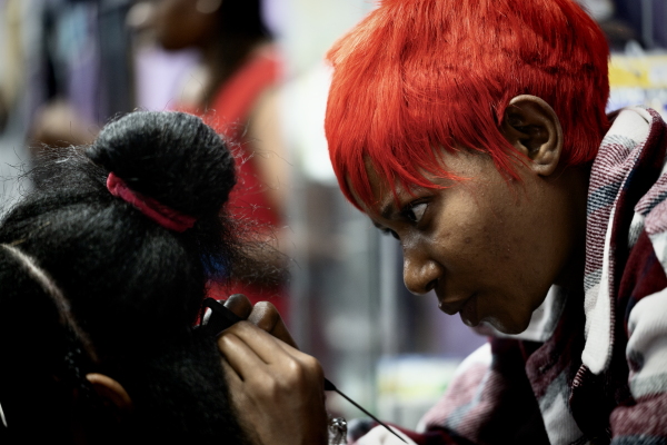 A woman braids a customer's hair at a salon.