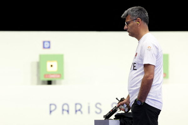 Turkey's Yusuf Dikec, wearing small yellow earplugs, eyeglasses and a white jersey, competes in the shooting 10m air pistol mixed team gold medal match at Chateauroux Shooting Center.