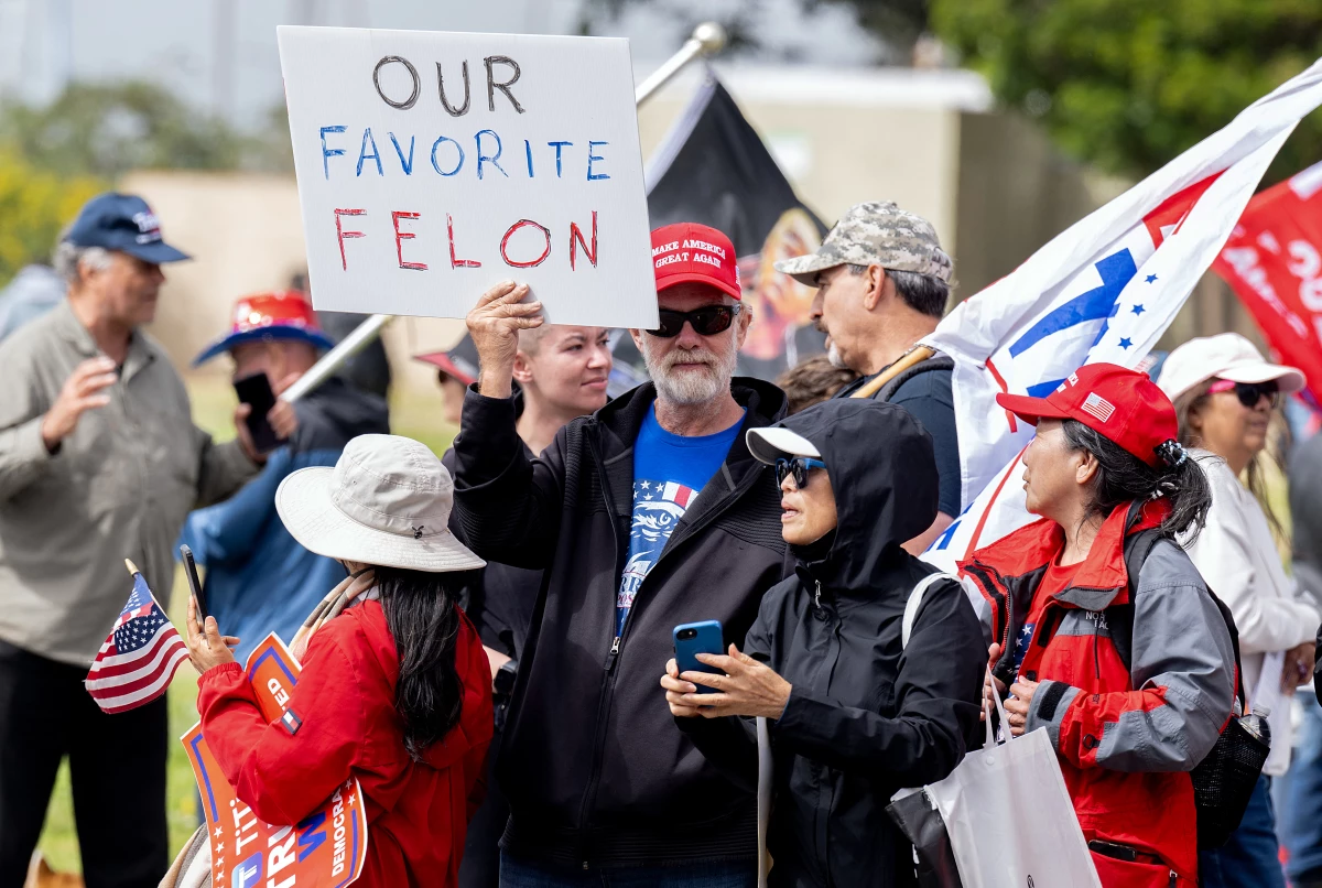 A supporter holds a sign reading 'Our Favorite Felon' outside a fundraising event for Donald Trump on Thursday.