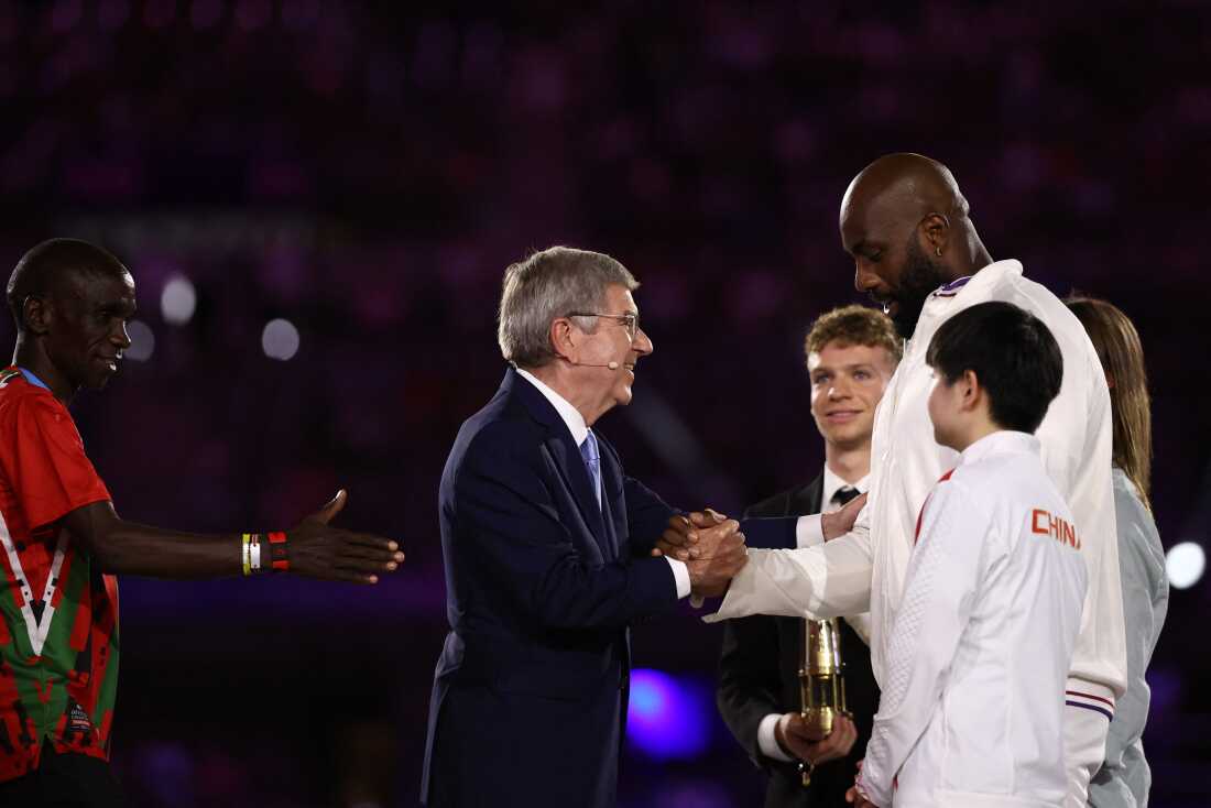 International Olympic Committe (IOC) President Thomas Bach (C) shakes hands with France's judoka Teddy Riner on Sunday.