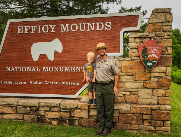 Brian Gibbs, pictured with his son Oliver in front of the Effigy Mounds National Monument park sign, in July 2024.