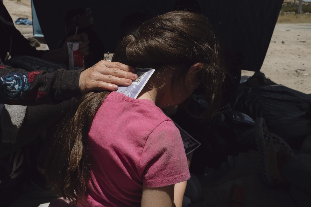 A mother tries to cool her child with an icepack, after crossing the desert in the San Diego sector of the U.S.-Mexico border during a heat wave.