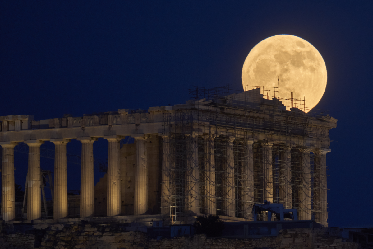 The strawberry Moon rises in the sky behind the 5th century B.C. Parthenon temple at the ancient Acropolis hill, in Athens, Greece.