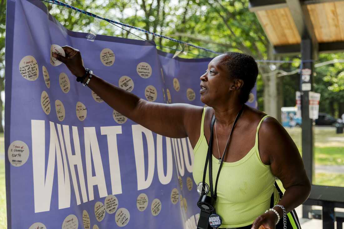 Rose Edwards, 66, puts a sticker with her hopes for the future on a banner at a community meetup event for Dr. Abdul El-Sayed in Rouge Park on July 26, 2026 in Detroit, Mich. “You have to get involved in the community, you can’t complain and then not get involved. I love him and he has my vote and I can't wait to see what he does when he gets to Washington,” Edwards said.