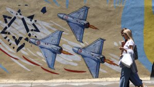 Iranian women walk past an anti-U.S. and anti-Israeli mural in Tehran. The military adviser to Iran's supreme leader on June 3, warned of more missile and drone strikes should the United States renew its attacks on Iran.